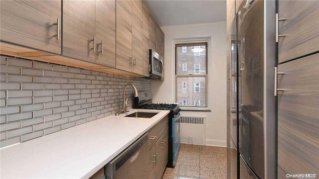 kitchen featuring backsplash, radiator, sink, and stainless steel appliances