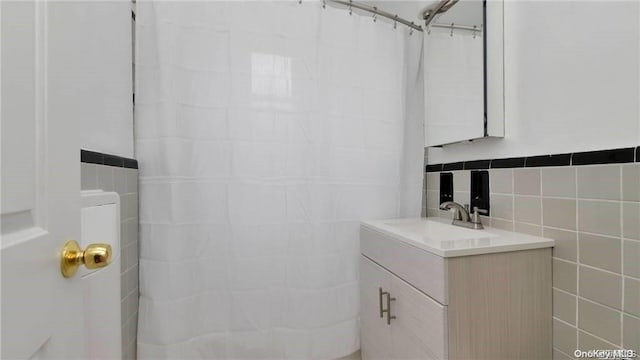 bathroom featuring walk in shower, vanity, and tile walls