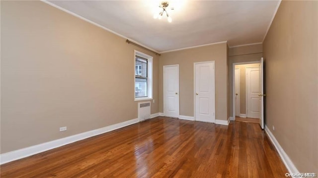 unfurnished bedroom with ornamental molding, radiator, and dark wood-type flooring