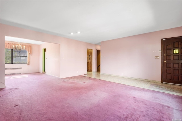 unfurnished room featuring light carpet, an inviting chandelier, and radiator