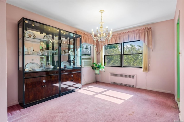 carpeted empty room with a notable chandelier and radiator