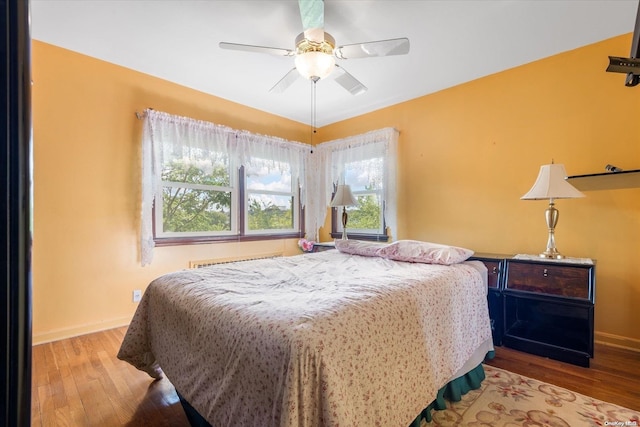 bedroom with radiator, light wood-type flooring, and ceiling fan