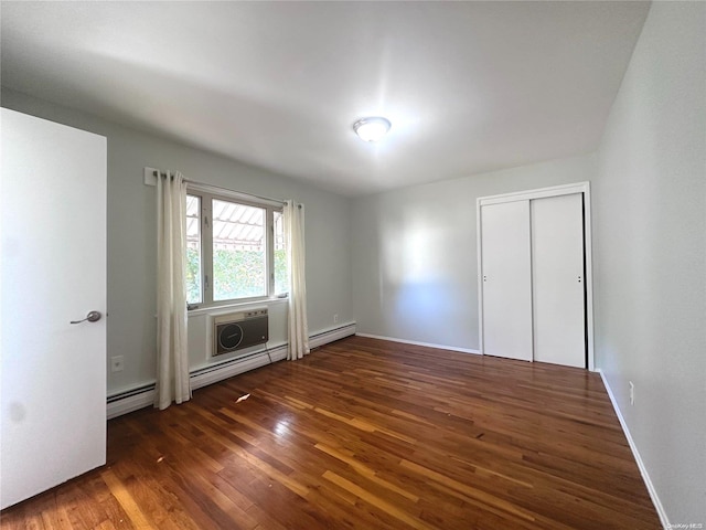 unfurnished bedroom featuring dark hardwood / wood-style floors, a wall unit AC, a closet, and a baseboard heating unit