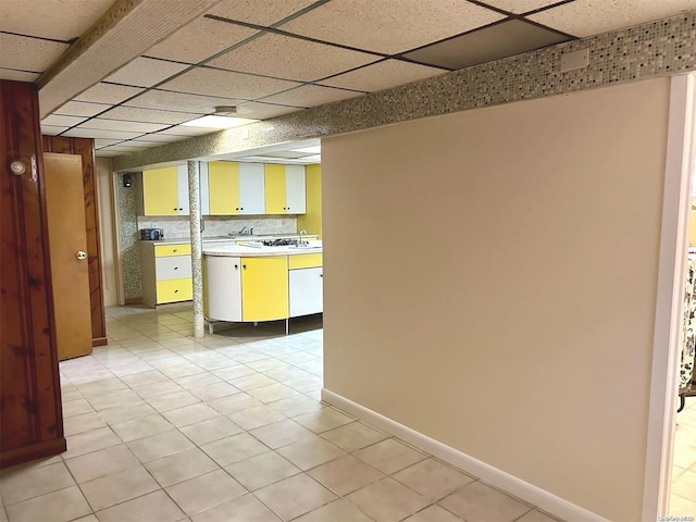 kitchen with a paneled ceiling, sink, light tile patterned floors, and backsplash