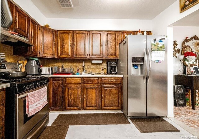 kitchen with sink, decorative backsplash, dark tile patterned floors, appliances with stainless steel finishes, and extractor fan