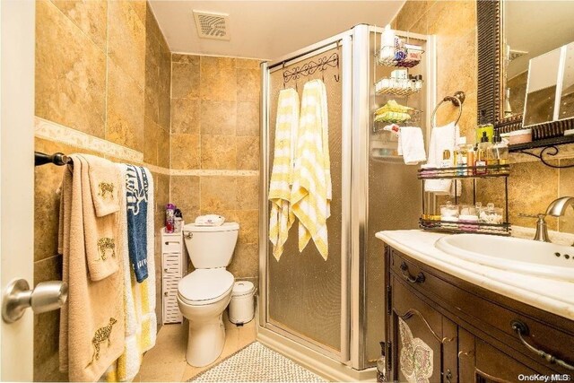 bathroom featuring tile patterned flooring, a shower with door, and tile walls