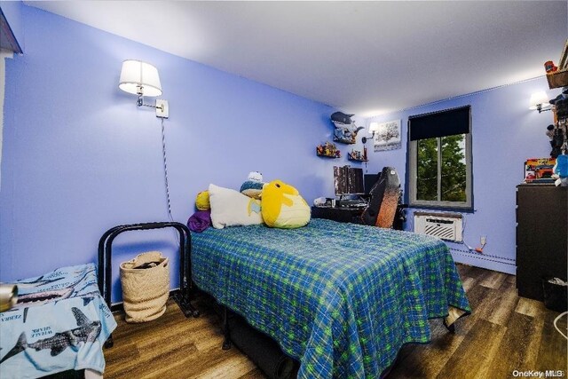 bedroom featuring dark hardwood / wood-style flooring and a wall mounted air conditioner