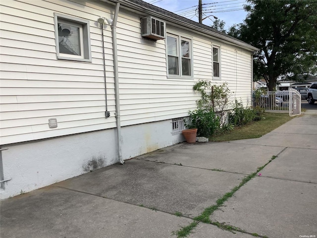 view of side of property featuring a patio area and a wall unit AC