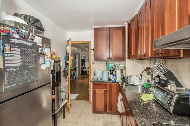 kitchen with decorative backsplash, ornamental molding, exhaust hood, sink, and dark stone countertops