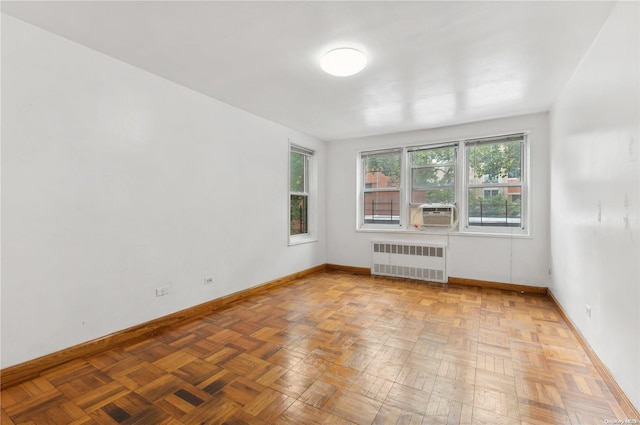 empty room with cooling unit, radiator, and light parquet floors