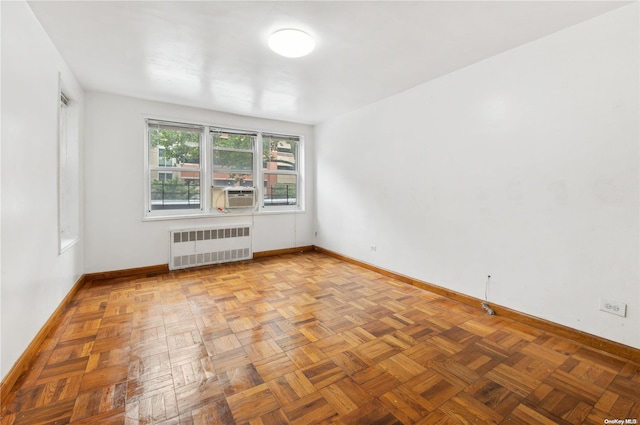 empty room featuring cooling unit, radiator, and light parquet floors