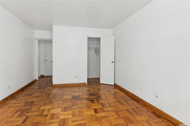 unfurnished bedroom featuring dark parquet floors and a closet