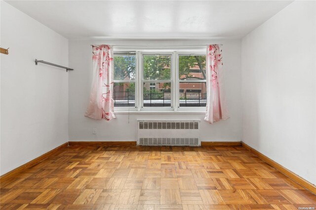 empty room with radiator heating unit and light parquet floors