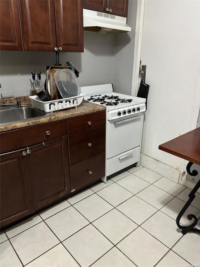 kitchen featuring white range with gas cooktop, sink, light tile patterned floors, and dark brown cabinets