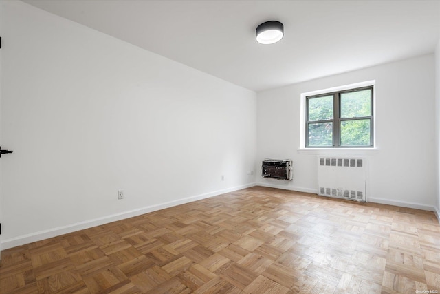 empty room with light parquet flooring, heating unit, and radiator