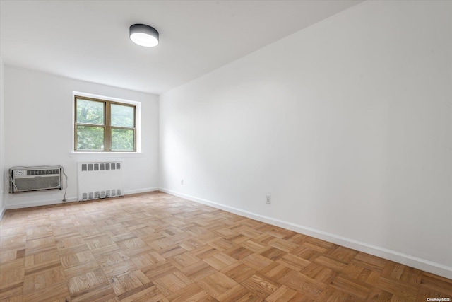 unfurnished room featuring light parquet flooring, radiator heating unit, and an AC wall unit