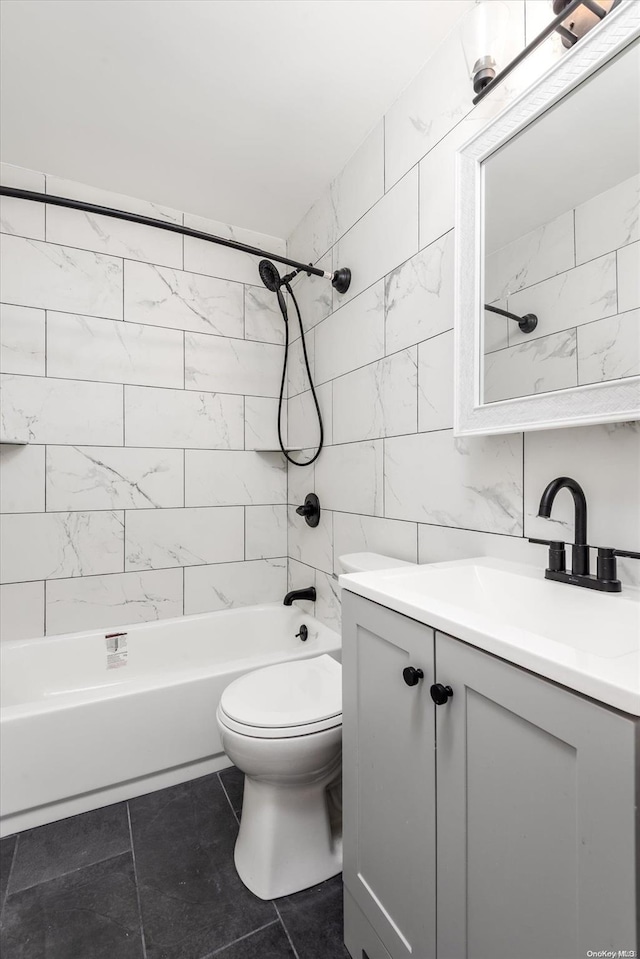 full bathroom with vanity, tile patterned floors, tiled shower / bath combo, toilet, and tile walls