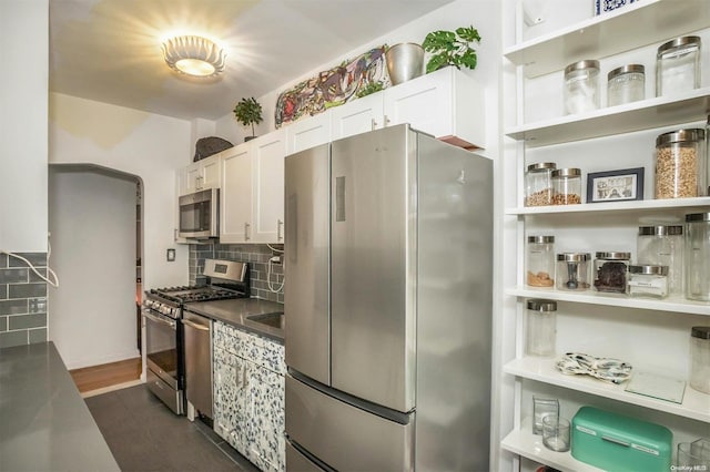 kitchen featuring white cabinets, appliances with stainless steel finishes, backsplash, and dark hardwood / wood-style flooring