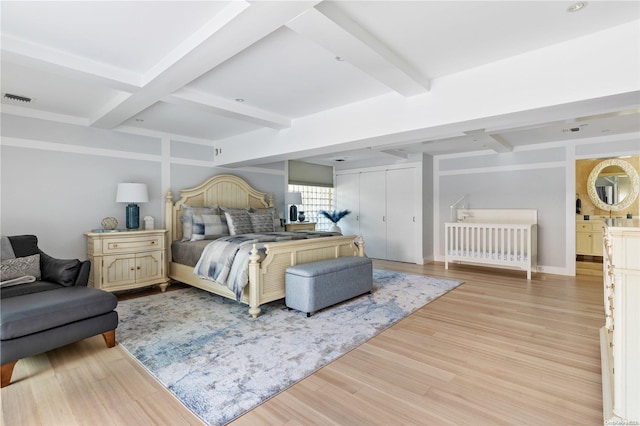 bedroom with beam ceiling, light hardwood / wood-style floors, and a closet