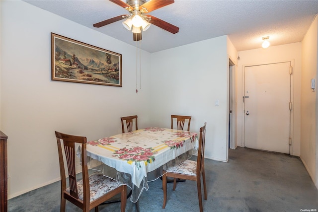 dining space featuring ceiling fan, dark carpet, and a textured ceiling