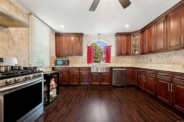 kitchen featuring dark wood-type flooring, crown molding, wall chimney exhaust hood, light stone countertops, and appliances with stainless steel finishes