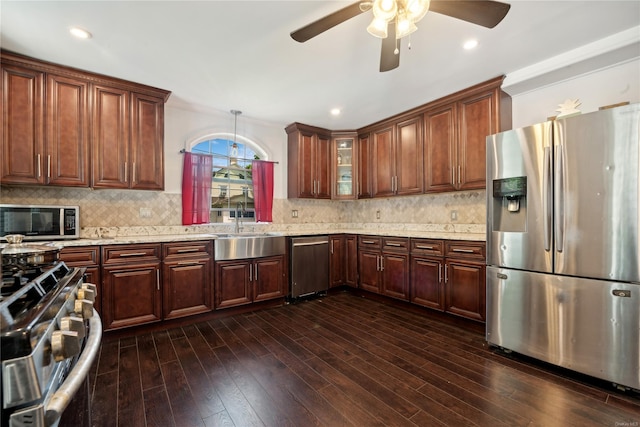 kitchen featuring dark wood-type flooring, sink, appliances with stainless steel finishes, tasteful backsplash, and light stone counters