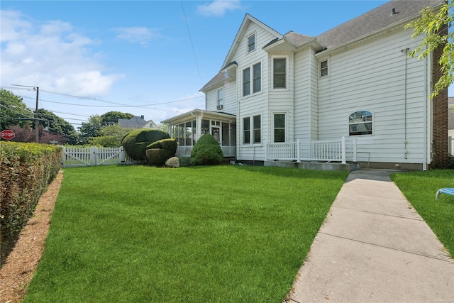 rear view of property with a yard and a sunroom