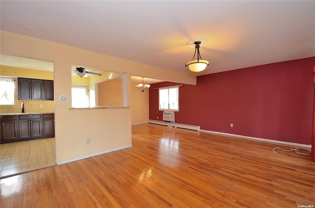 unfurnished living room featuring ceiling fan with notable chandelier, light hardwood / wood-style floors, a baseboard heating unit, and sink