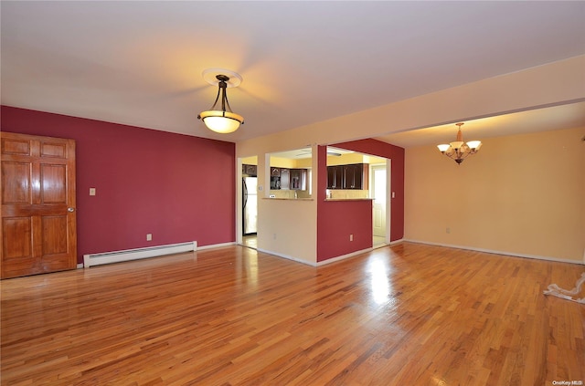 unfurnished living room featuring a notable chandelier, wood-type flooring, and a baseboard heating unit