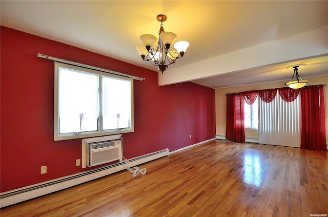 empty room with hardwood / wood-style flooring, an inviting chandelier, baseboard heating, and a wall unit AC