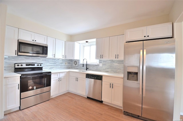 kitchen with white cabinets, appliances with stainless steel finishes, light wood-type flooring, and sink