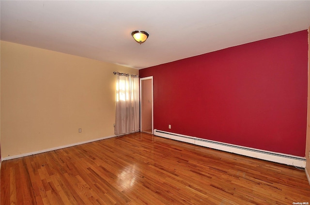 empty room with hardwood / wood-style floors and a baseboard heating unit