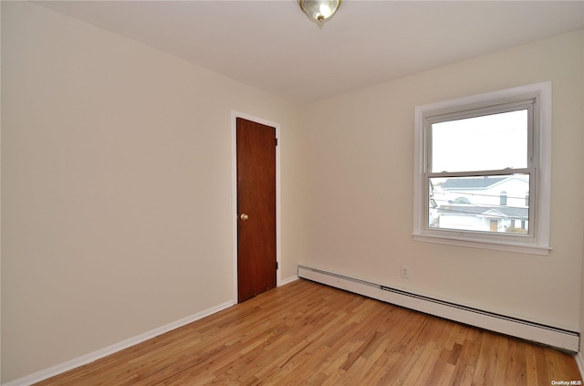 unfurnished room with light wood-type flooring and a baseboard radiator