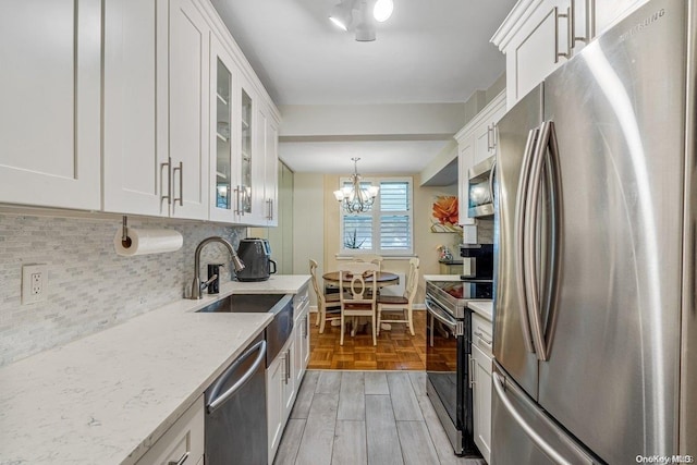 kitchen with appliances with stainless steel finishes, light hardwood / wood-style flooring, white cabinetry, and hanging light fixtures