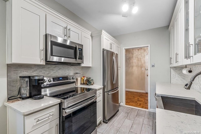 kitchen with light stone countertops, sink, white cabinetry, and stainless steel appliances