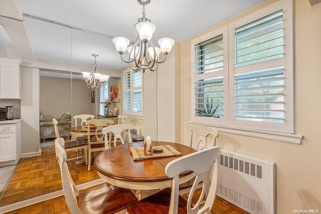 dining space featuring radiator, a wealth of natural light, parquet flooring, and a notable chandelier