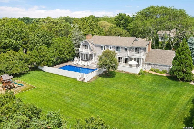 back of house featuring a balcony and a yard