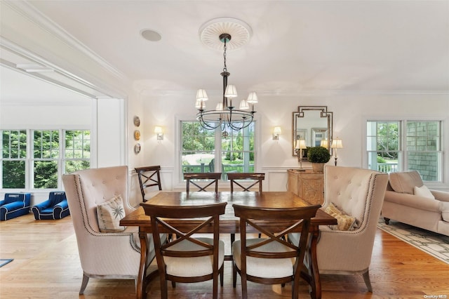 dining room featuring light wood-type flooring, crown molding, and an inviting chandelier