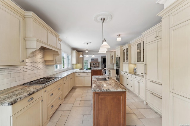 kitchen with sink, hanging light fixtures, an island with sink, tasteful backsplash, and stainless steel appliances