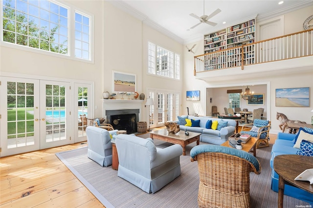 living room with french doors, hardwood / wood-style flooring, ceiling fan, a towering ceiling, and ornamental molding