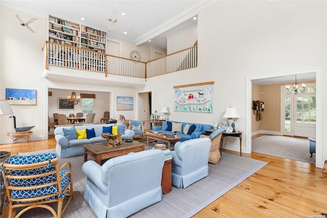 living room featuring crown molding, wood-type flooring, a high ceiling, and a notable chandelier