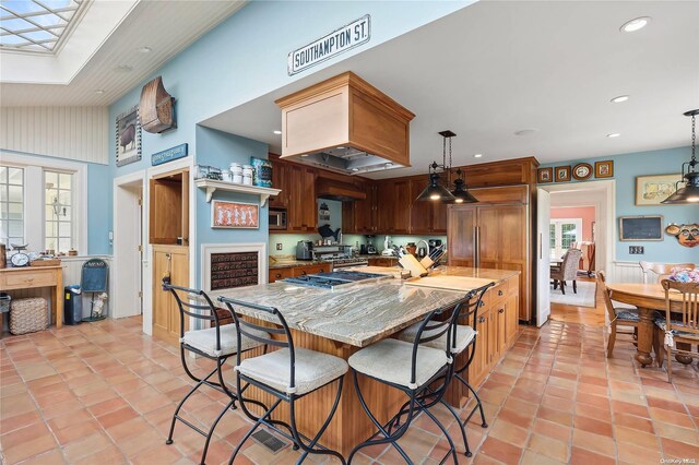 kitchen with pendant lighting, light stone countertops, high vaulted ceiling, and a skylight