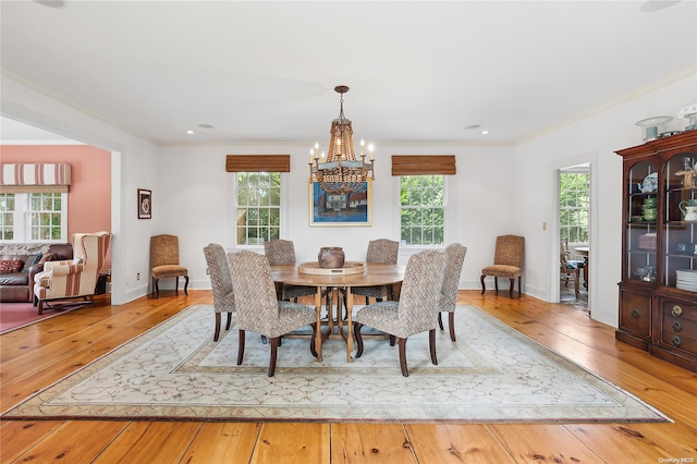 dining space with light hardwood / wood-style floors, ornamental molding, and a notable chandelier