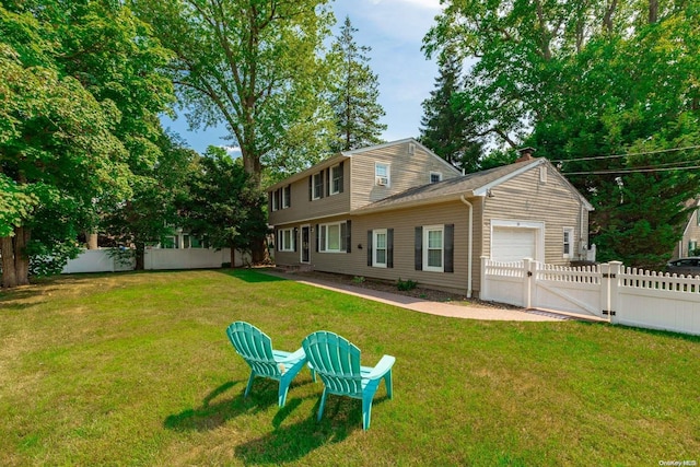 rear view of house featuring a yard and a garage