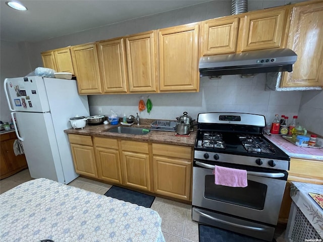 kitchen featuring gas stove, sink, backsplash, white fridge, and light tile patterned floors