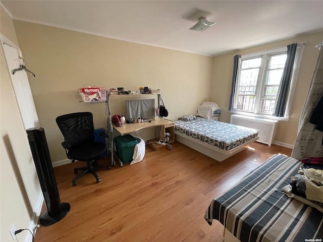 bedroom featuring radiator heating unit and light hardwood / wood-style floors