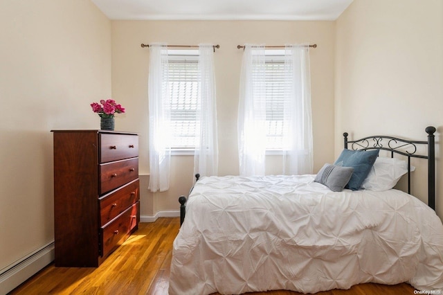 bedroom with a baseboard radiator and light hardwood / wood-style flooring