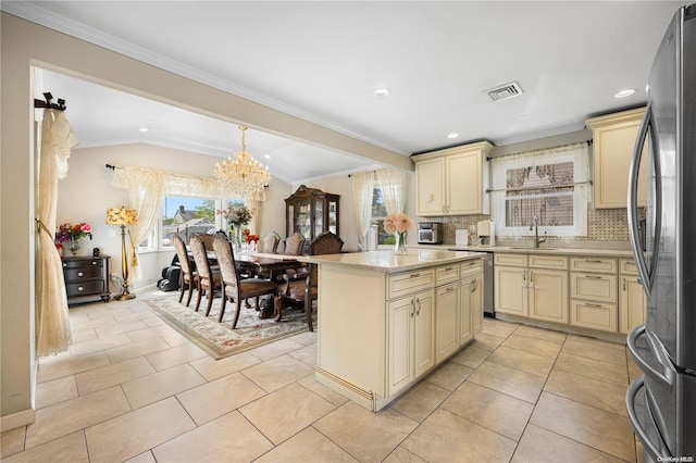 kitchen featuring cream cabinetry, decorative backsplash, a center island, and vaulted ceiling