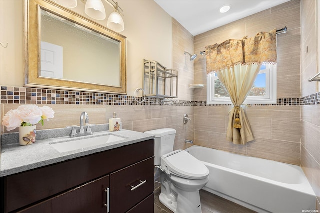 full bathroom with tiled shower / bath, vanity, toilet, and tile walls