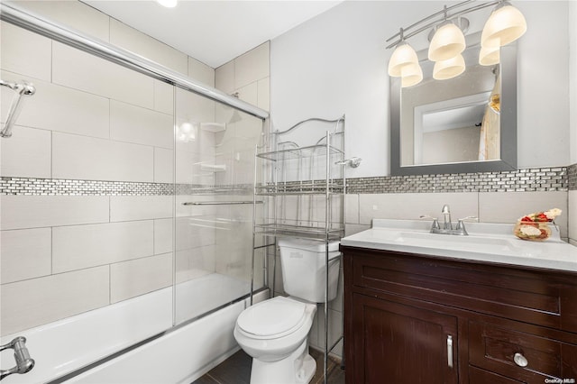 full bathroom with shower / bath combination with glass door, vanity, tile walls, and toilet